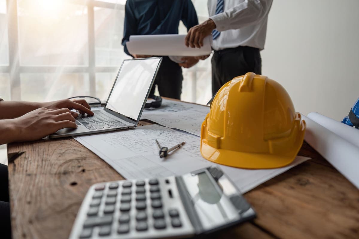 Hard hat, calculator, and plans on a contractor's desk