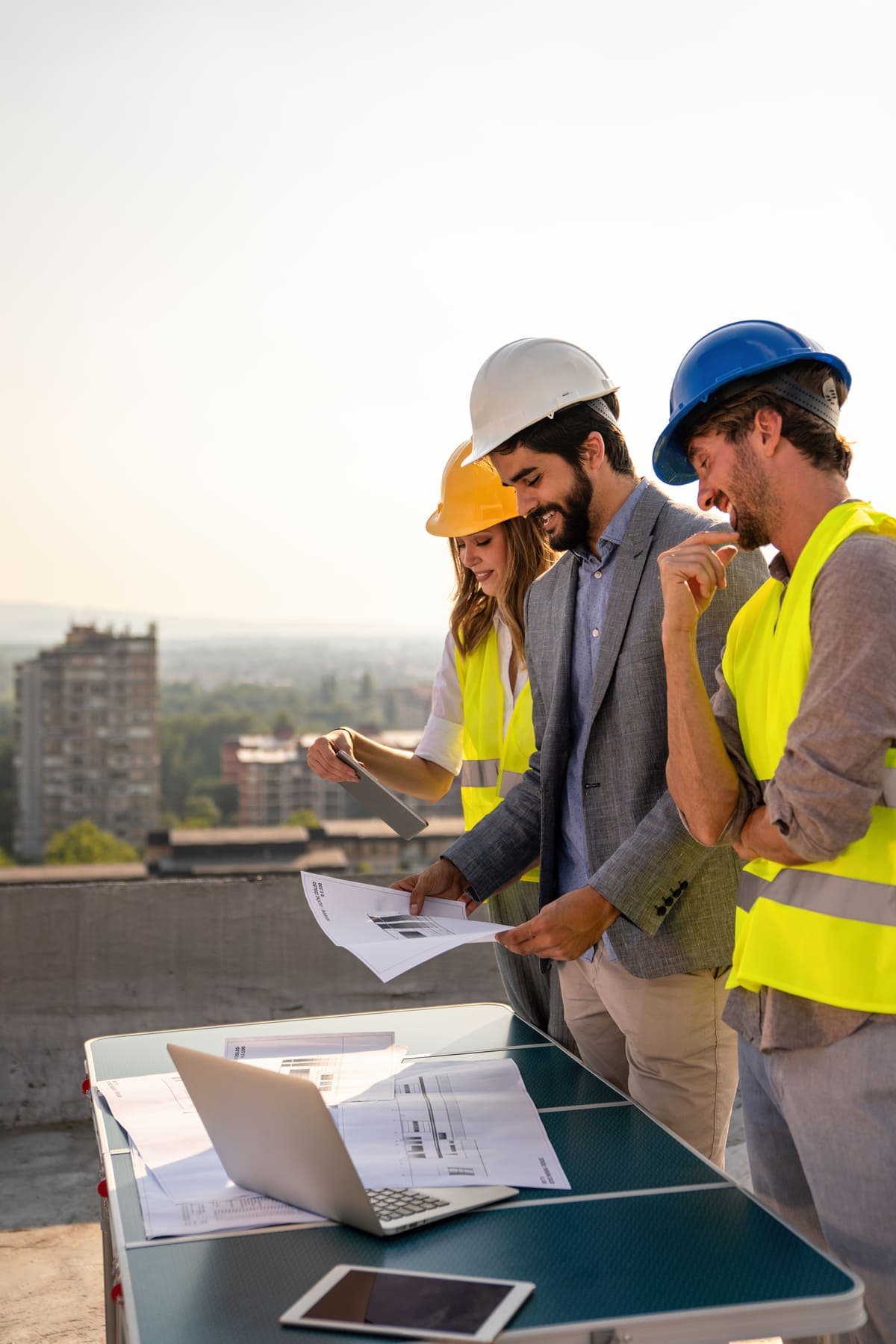 Contractors reviewing plans on a job site rooftop