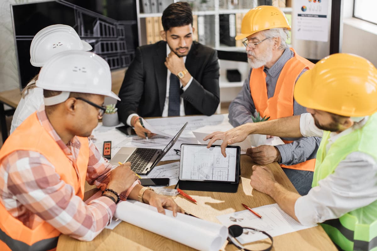 Project managers and an auditor meeting over plans