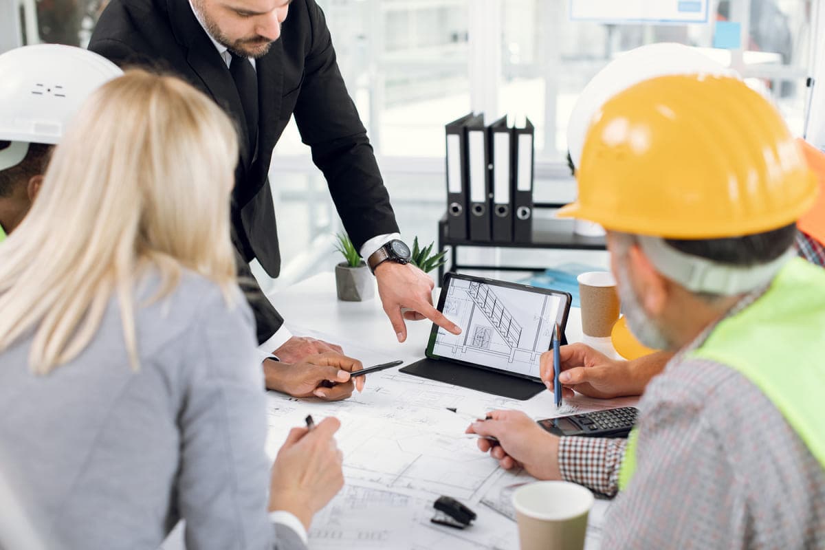 Contractors and a CPA reviewing project plans on a tablet