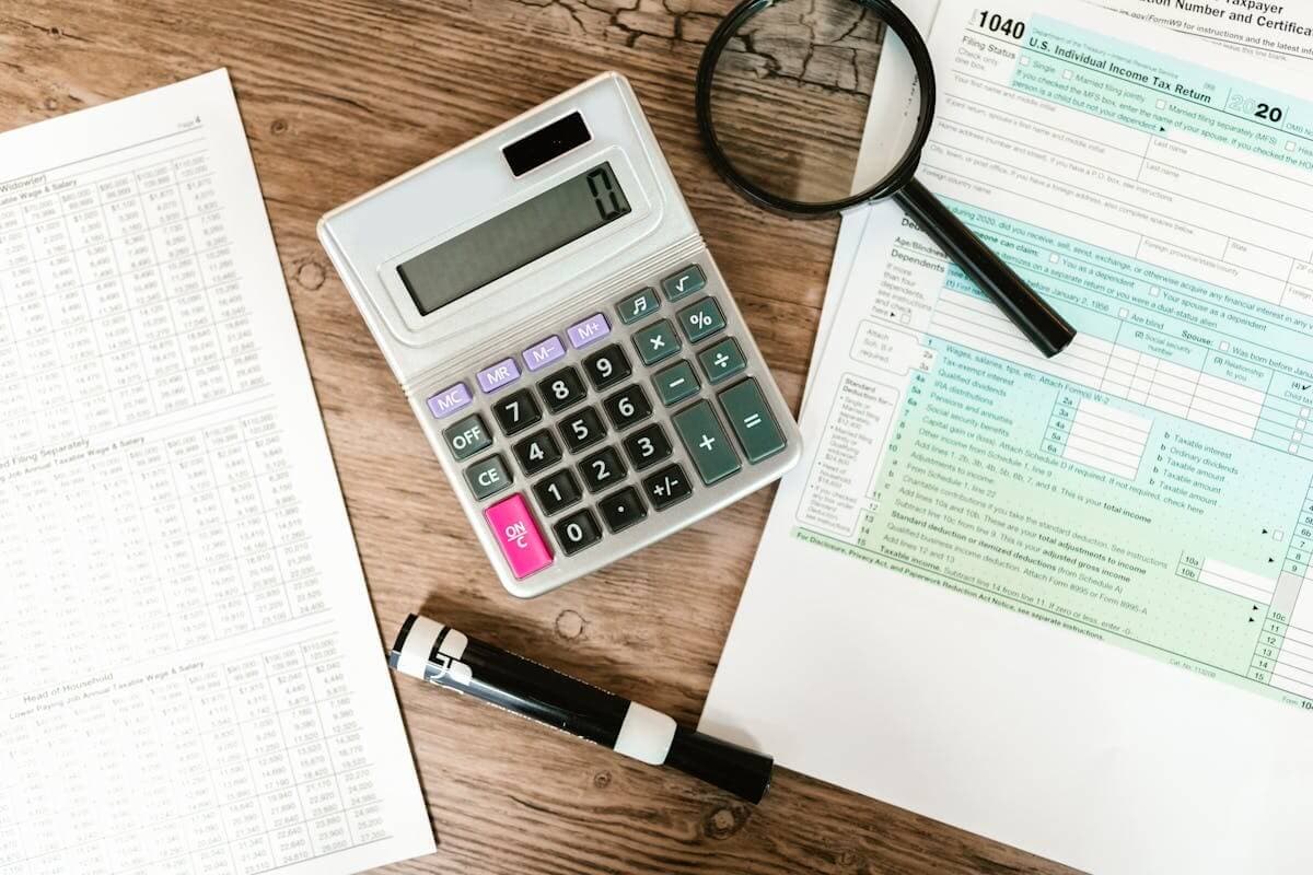 A tax return beside a calculator and magnifier on a desk